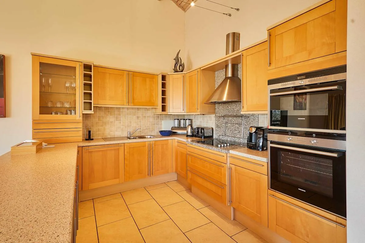 A fitted kitchen with wooden cabinets, a range hood, and built-in ovens.