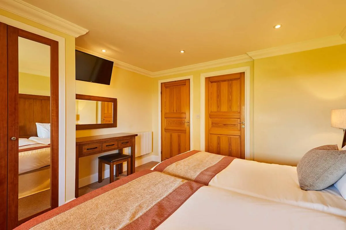 A bedroom with two beds, wooden doors, and a dressing table.
