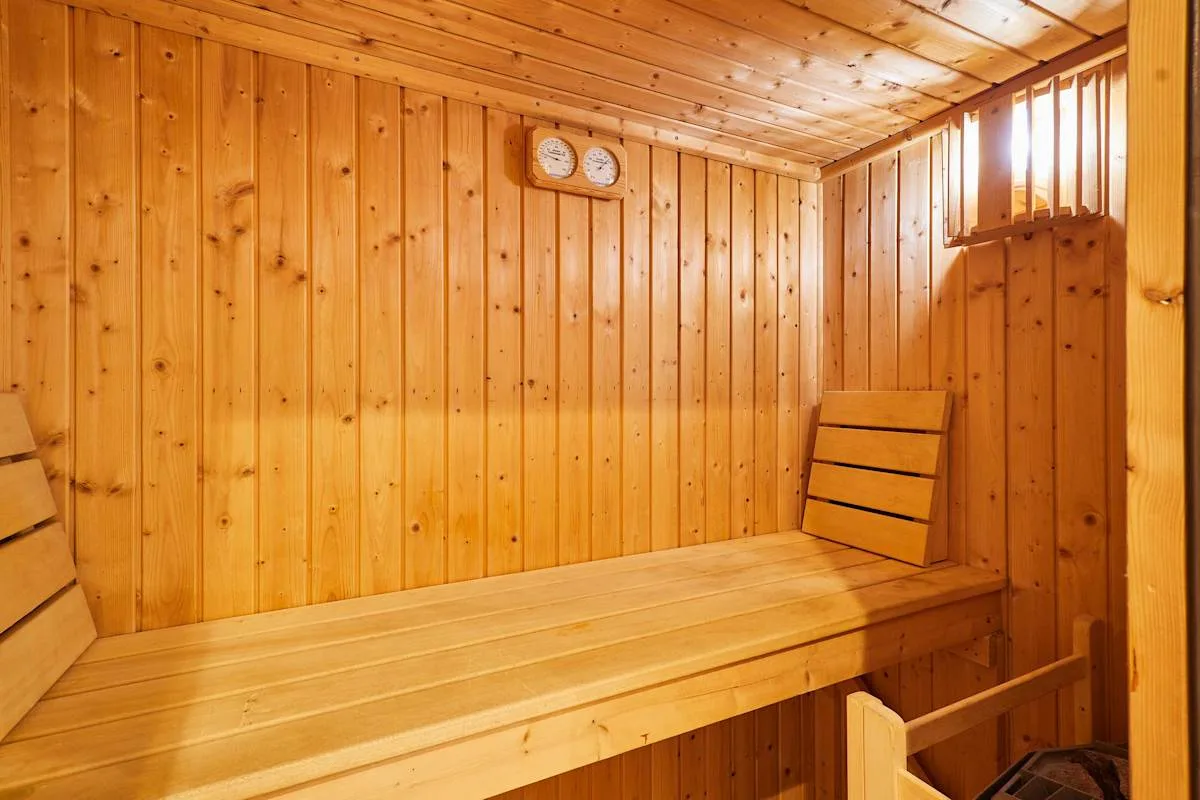 A wood-paneled sauna room with a long wooden bench and wall clock.