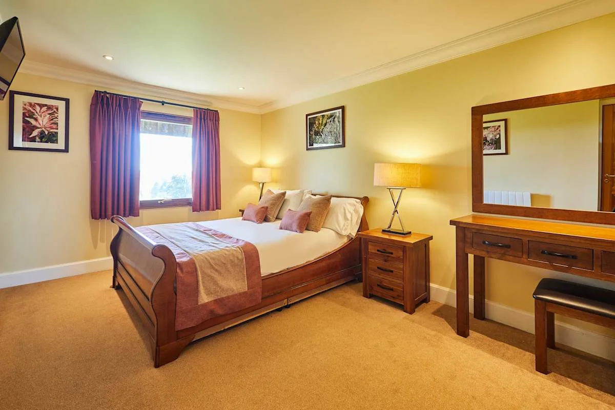 A bedroom with a bed, bedside tables, and a dressing table.