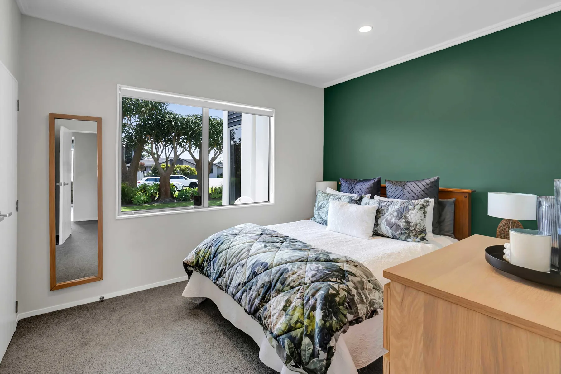 Un dormitorio con una cama, una pared verde y una ventana grande.