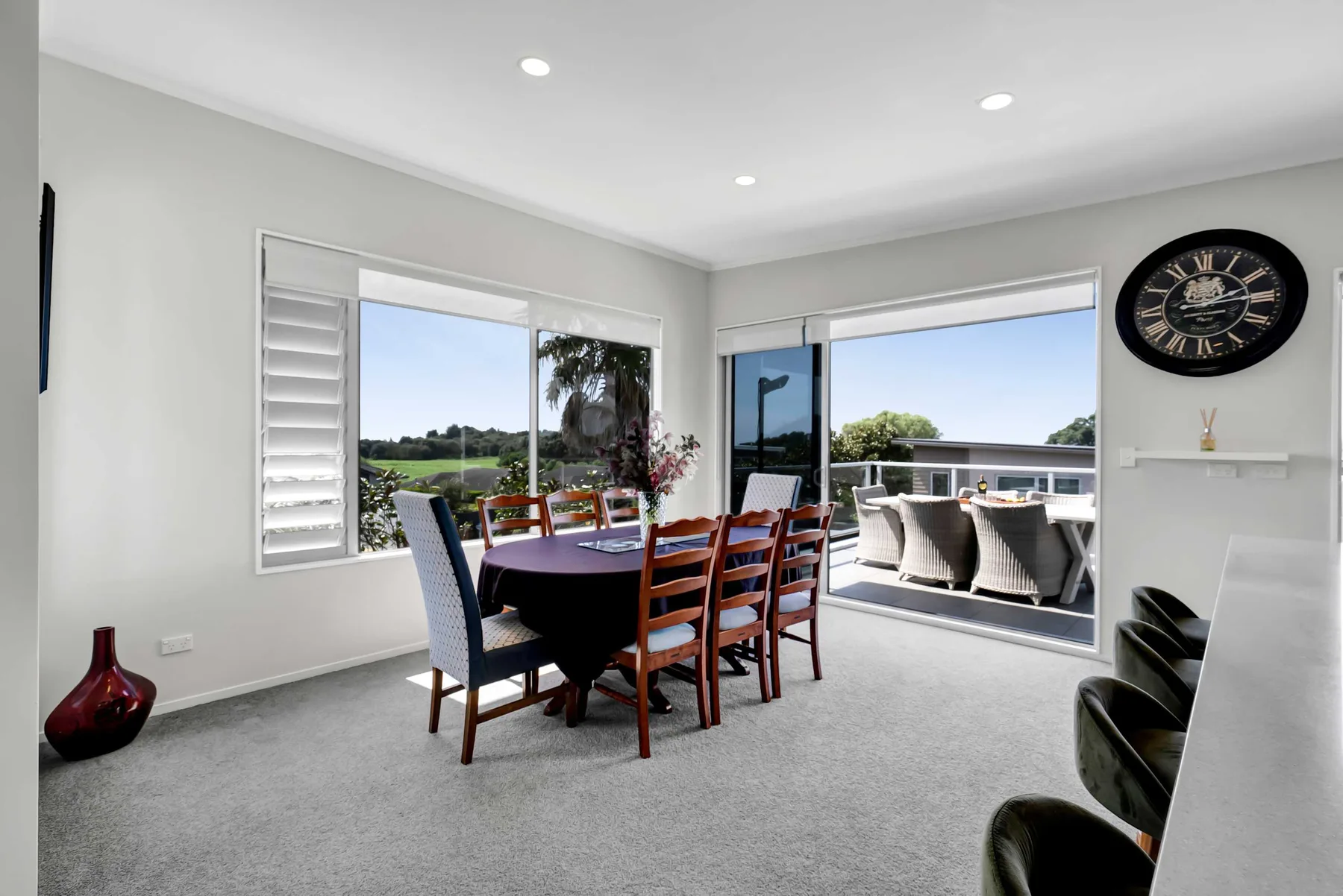 Comedor con una mesa junto a grandes ventanales que dan a una terraza exterior.