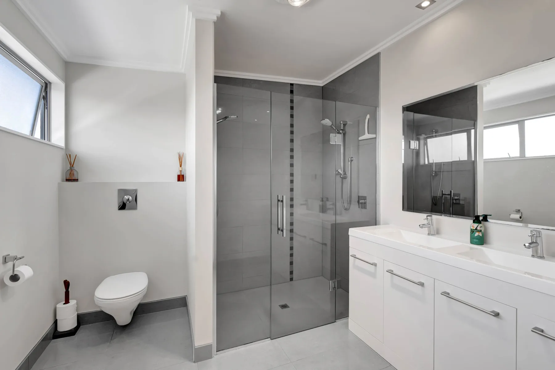 Un baño moderno con una ducha de vidrio y un tocador blanco.