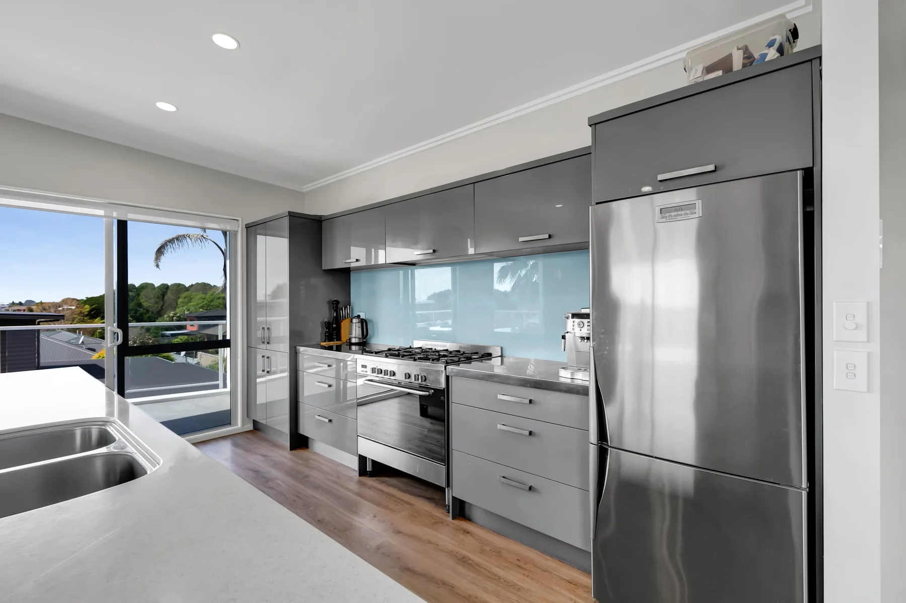 Una cocina moderna con gabinetes grises, electrodomésticos de acero inoxidable y una ventana amplia.