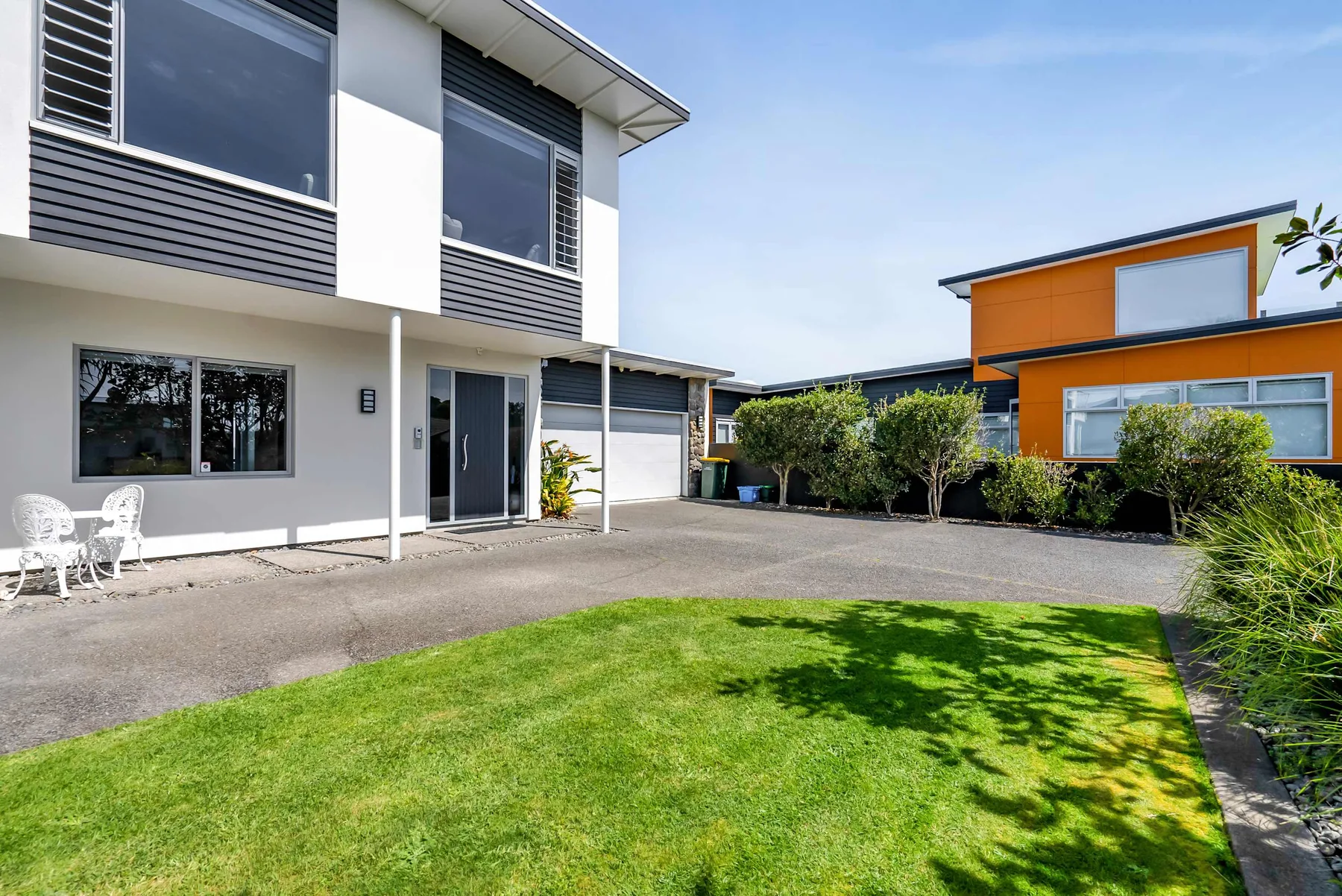 Casas modernas rodean un patio pavimentado con césped y asientos al aire libre.