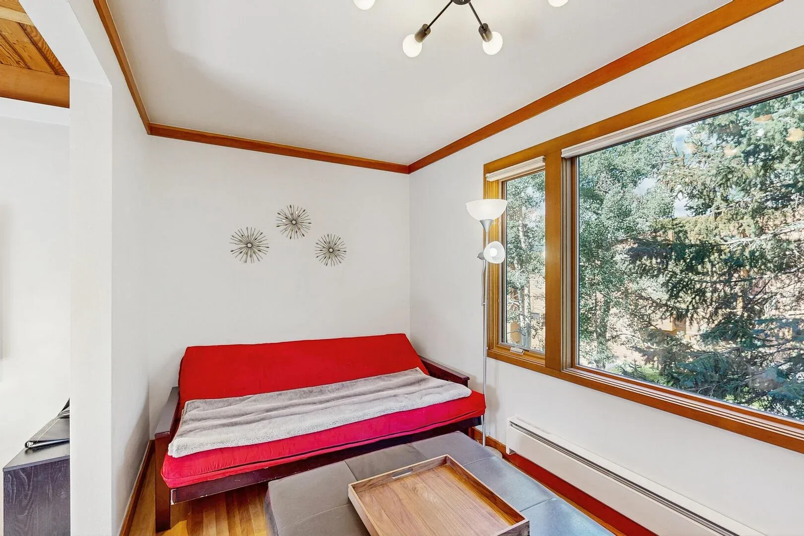 A bedroom with a red bed beneath large windows.