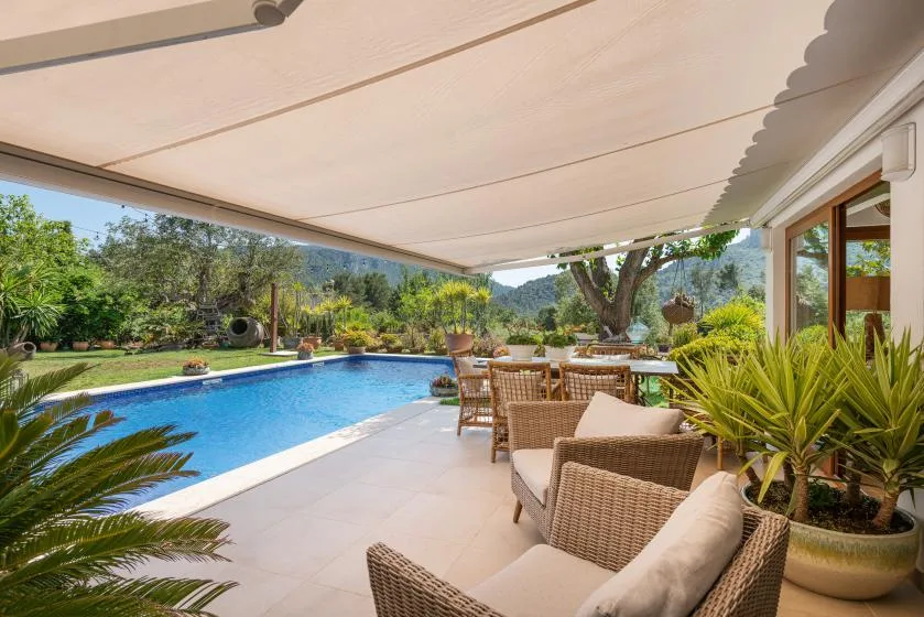 A poolside patio with outdoor seating under a large shade canopy.