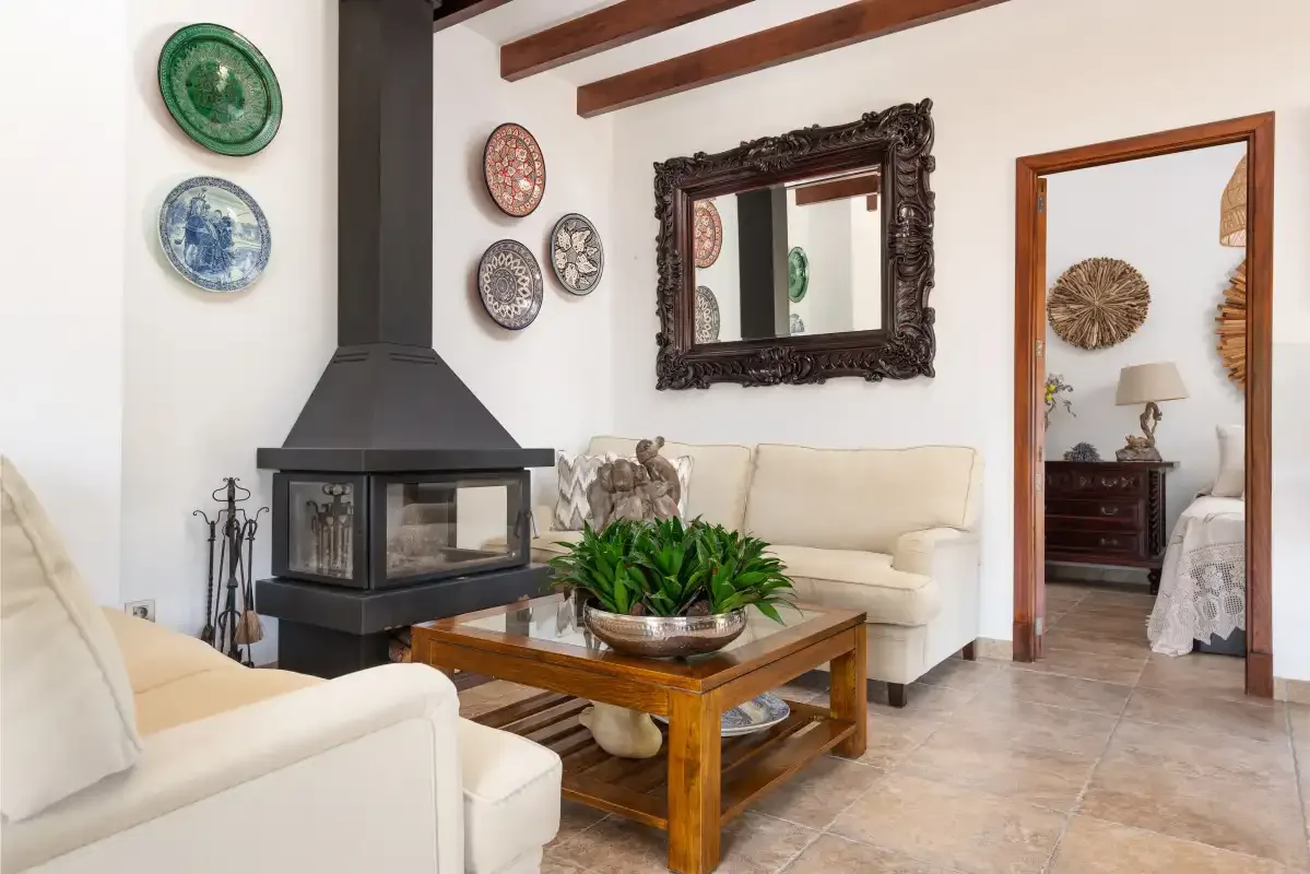 A living room with white seating, a fireplace, and a wooden coffee table.