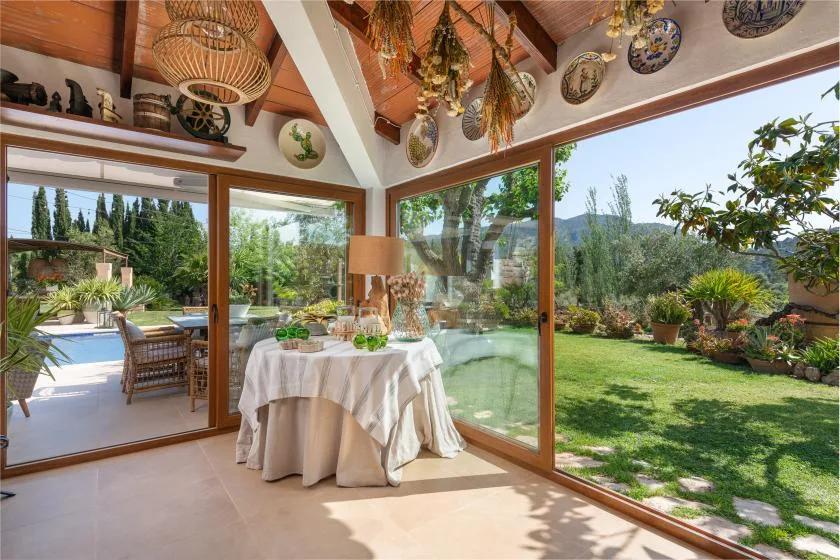 A sunlit dining area opens through glass doors onto a garden.