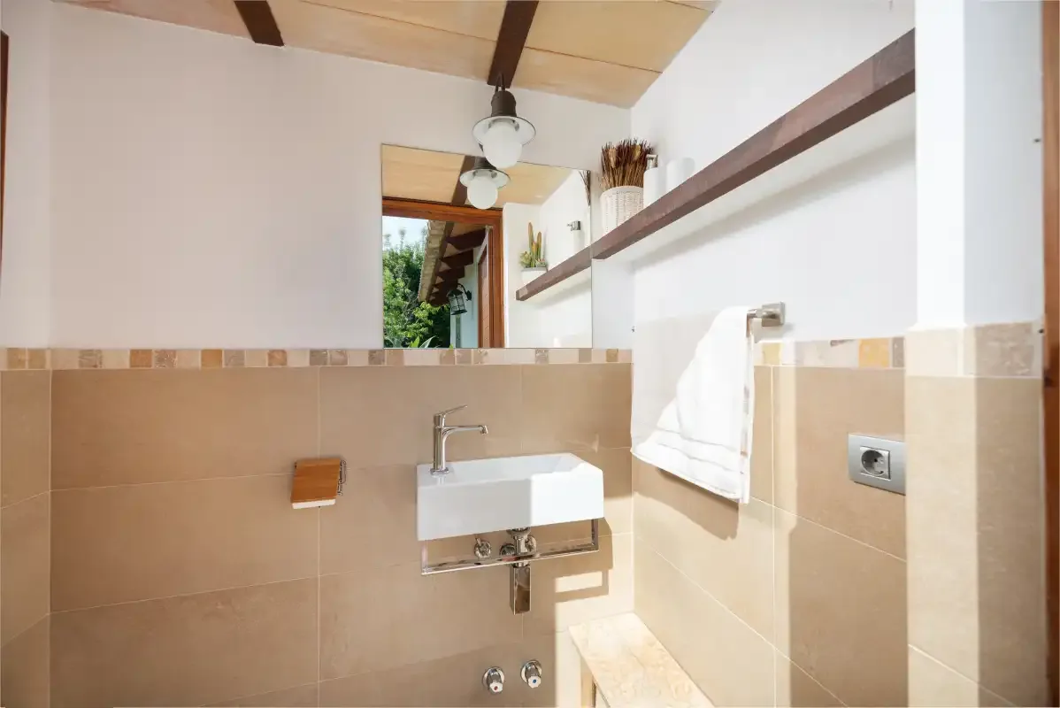 A tiled bathroom with a wall-mounted sink and mirror.