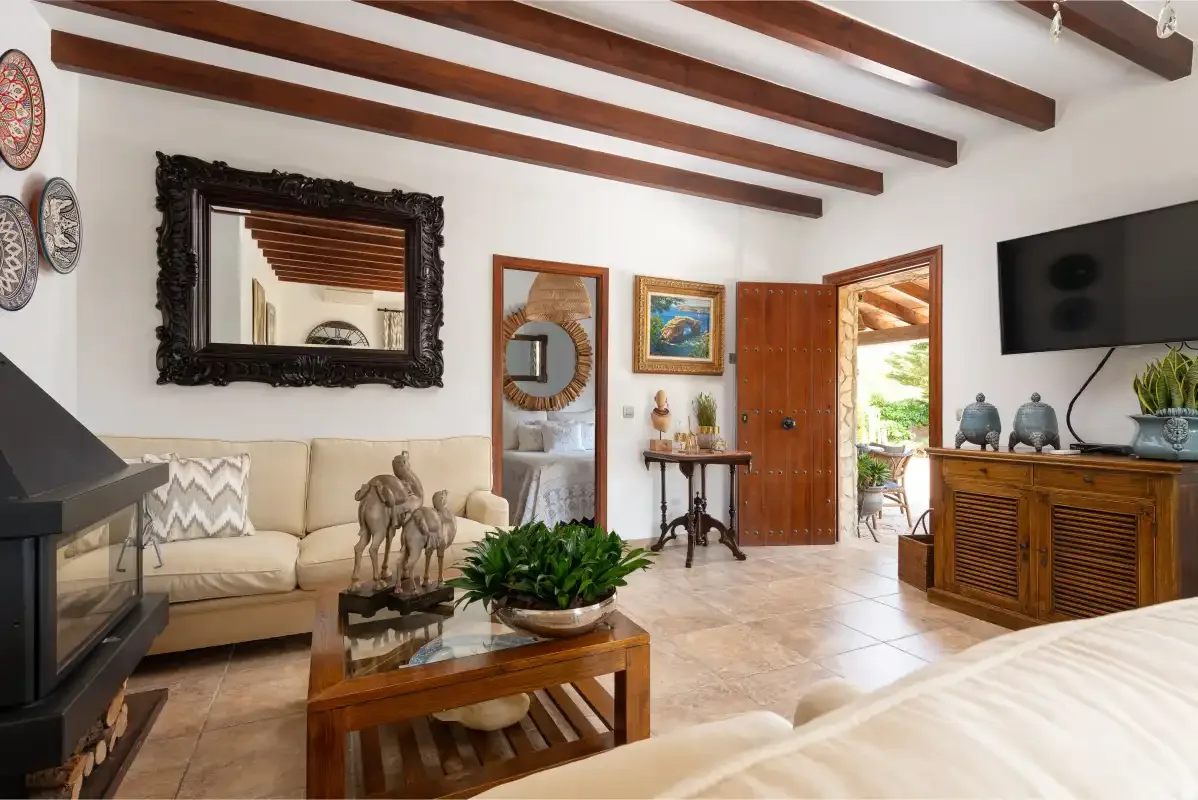 A living room with cream seating, exposed ceiling beams, and a wooden coffee table.