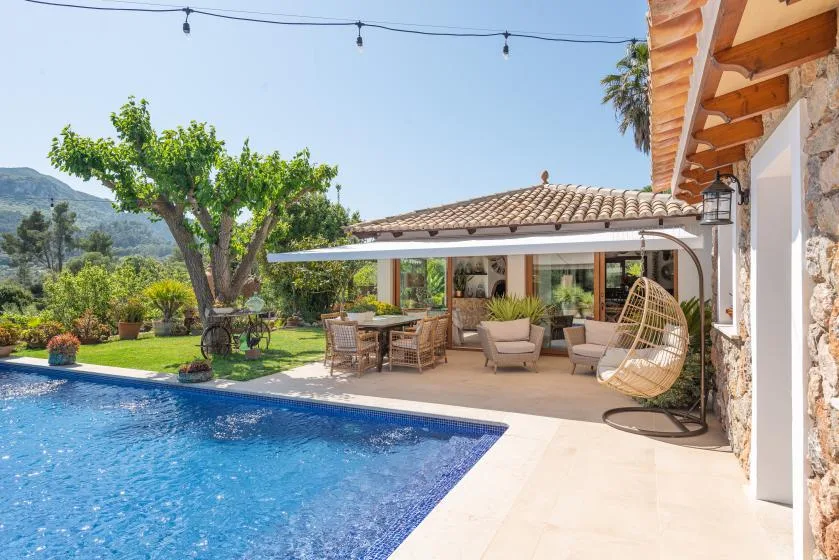 Outdoor patio seating beside a swimming pool, with a shaded dining area.