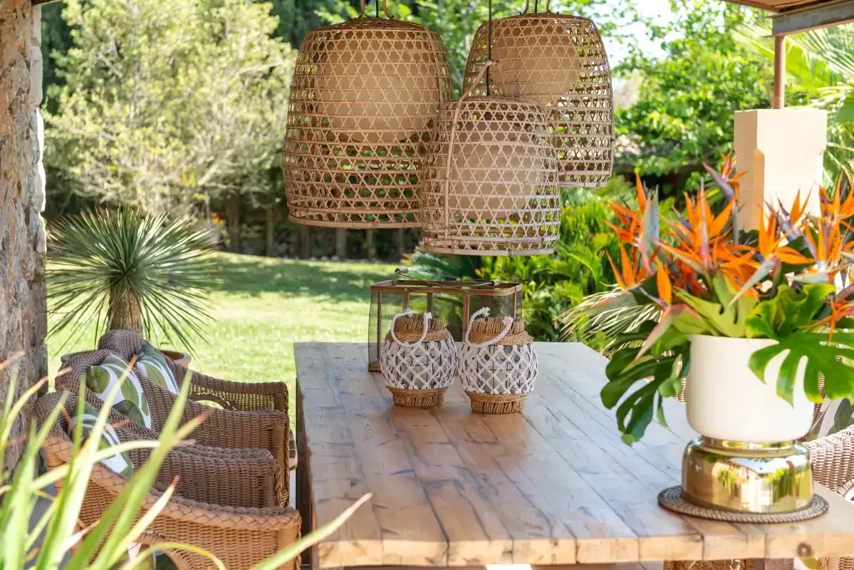 A garden patio dining table sits among greenery and flowering plants.