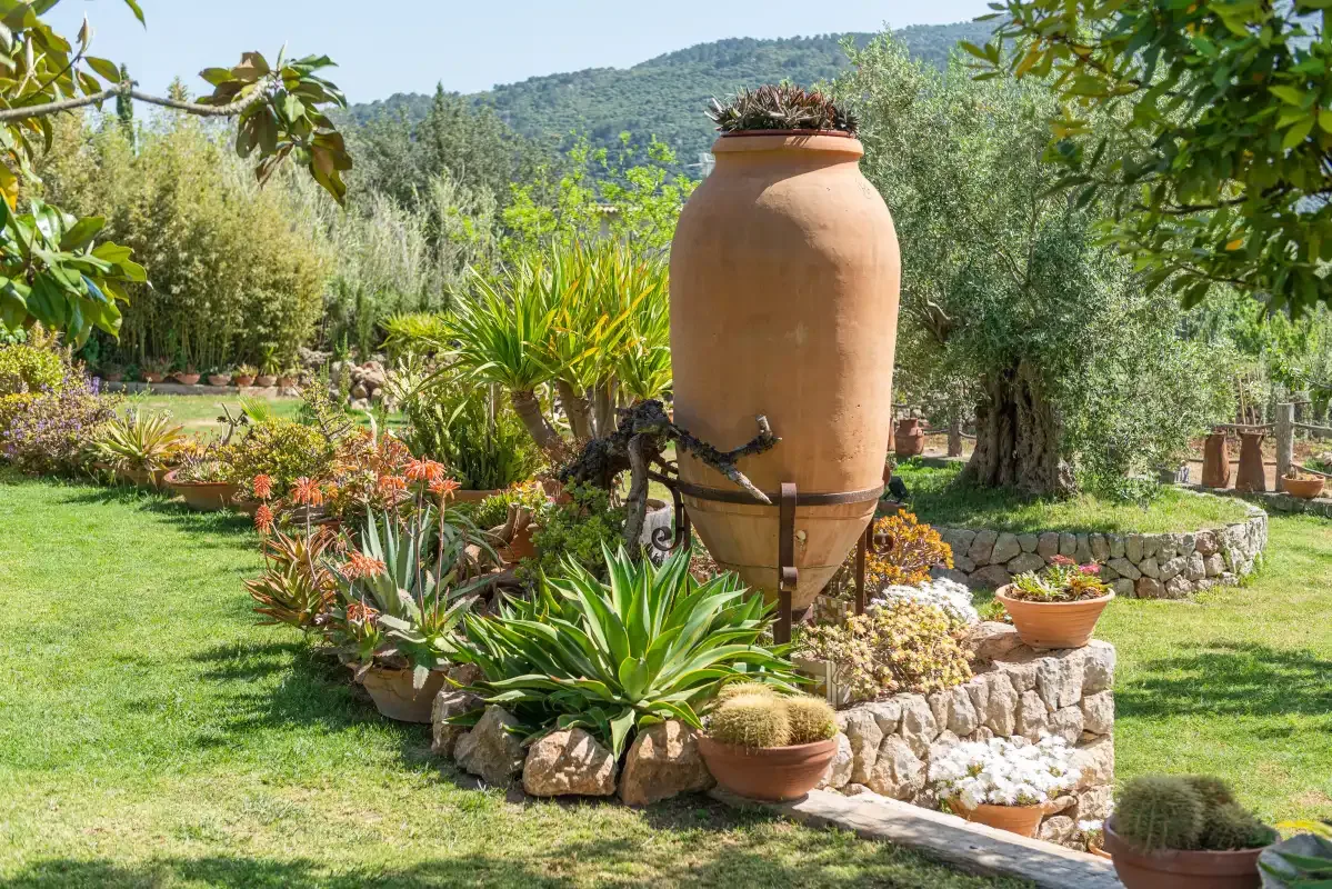 A garden with a large terracotta urn surrounded by plants and flowers.