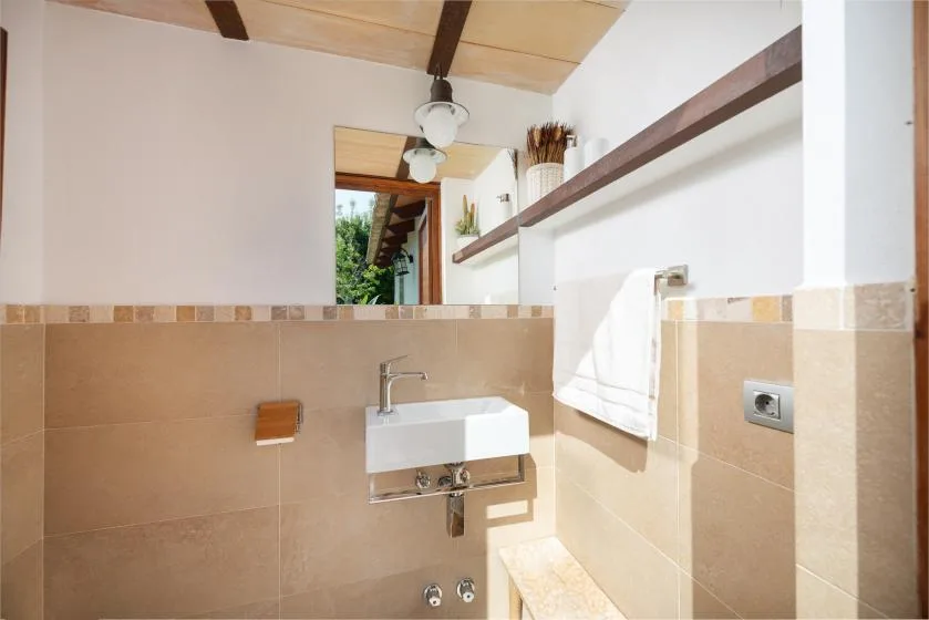 A bathroom with a wall-mounted sink and a towel hanging nearby.
