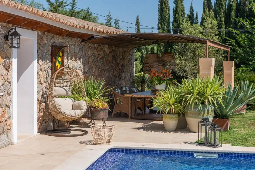 A stone patio with an outdoor dining table and a swimming pool.