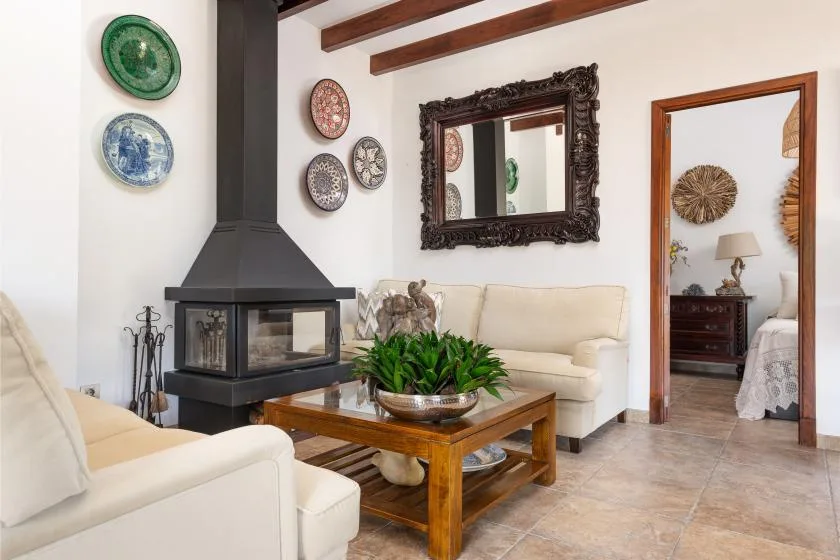 A living room with cream seating, a glass-fronted fireplace, and a wooden coffee table.