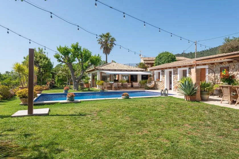 A landscaped courtyard with a swimming pool, lawn, and string lights.
