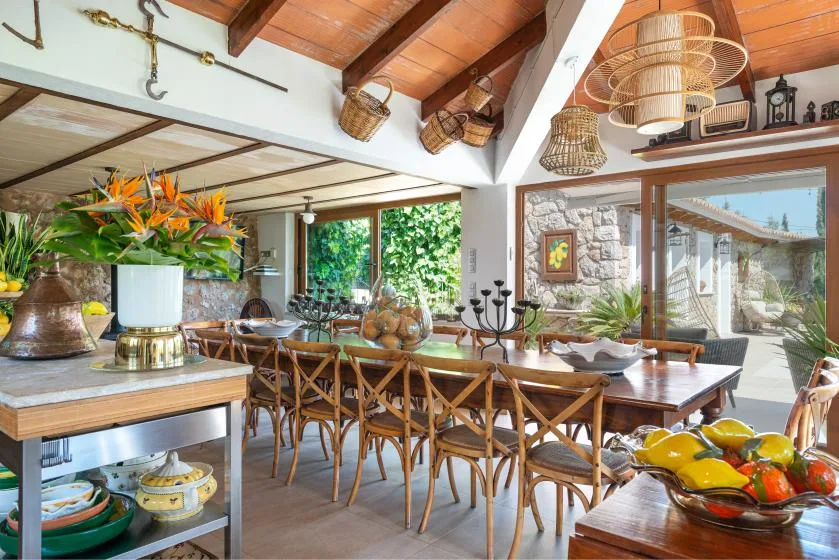 A dining room with a long wooden table and chairs beneath exposed beams.