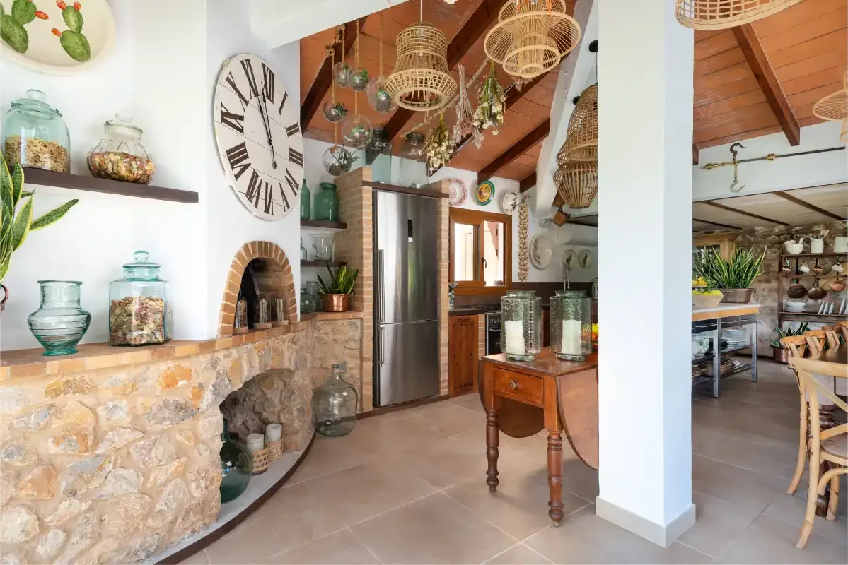 A rustic kitchen with a stone counter, stainless steel refrigerator, and wooden ceiling beams.