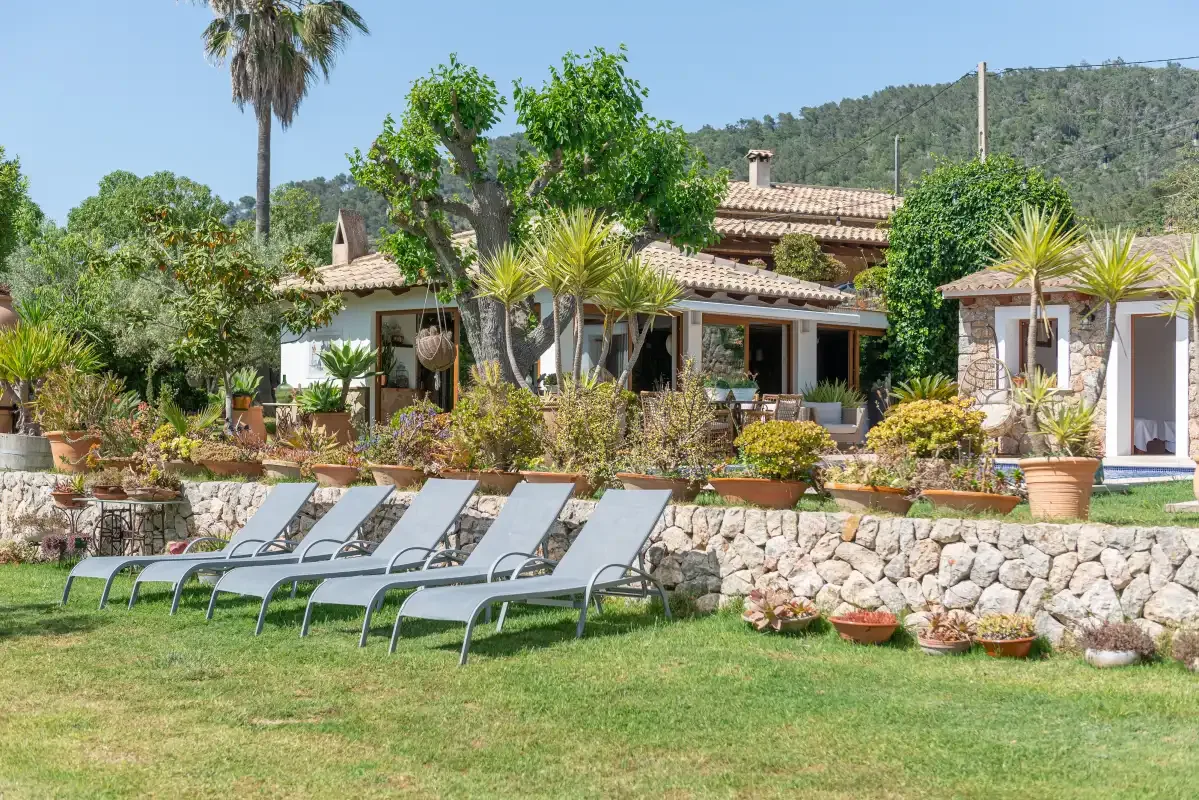 A landscaped garden with reclining seating sits in front of a house.