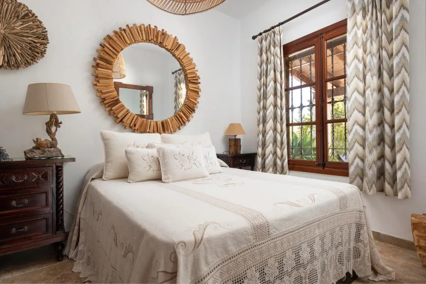 A bright bedroom with a neatly made bed beside a large window.