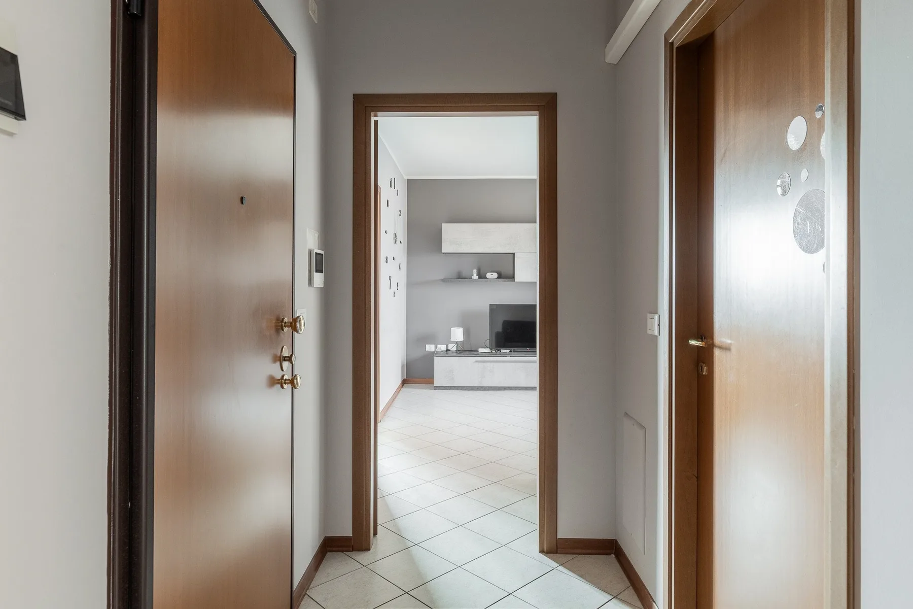 Un pasillo con puertas abiertas que dan a una cocina luminosa.