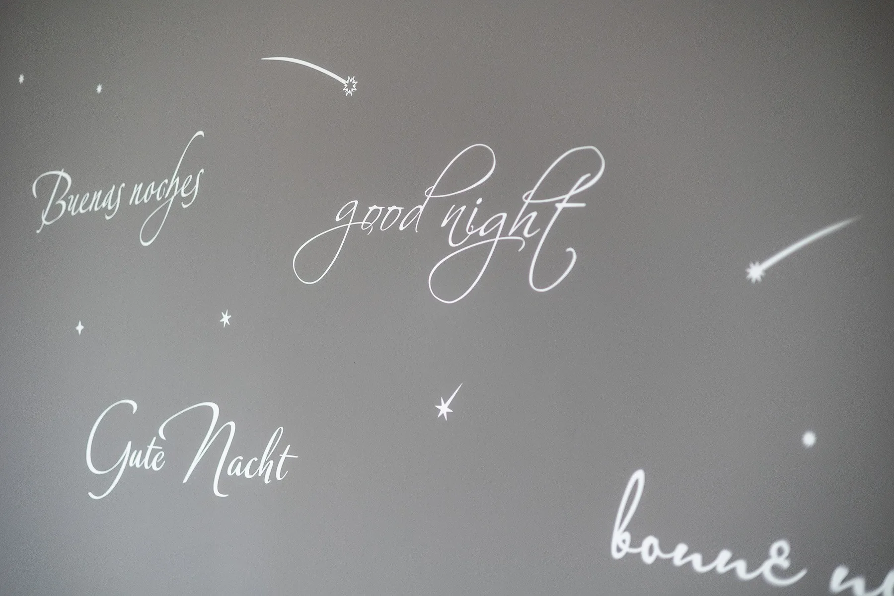 Una pared gris muestra letras decorativas de «buenas noches» y pequeños motivos de estrellas.