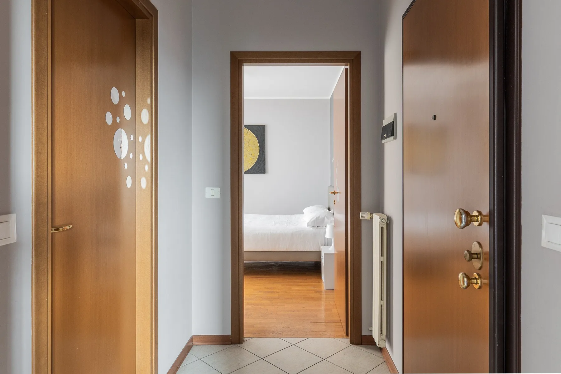 Un pasillo conduce por una puerta abierta a un dormitorio con una cama.