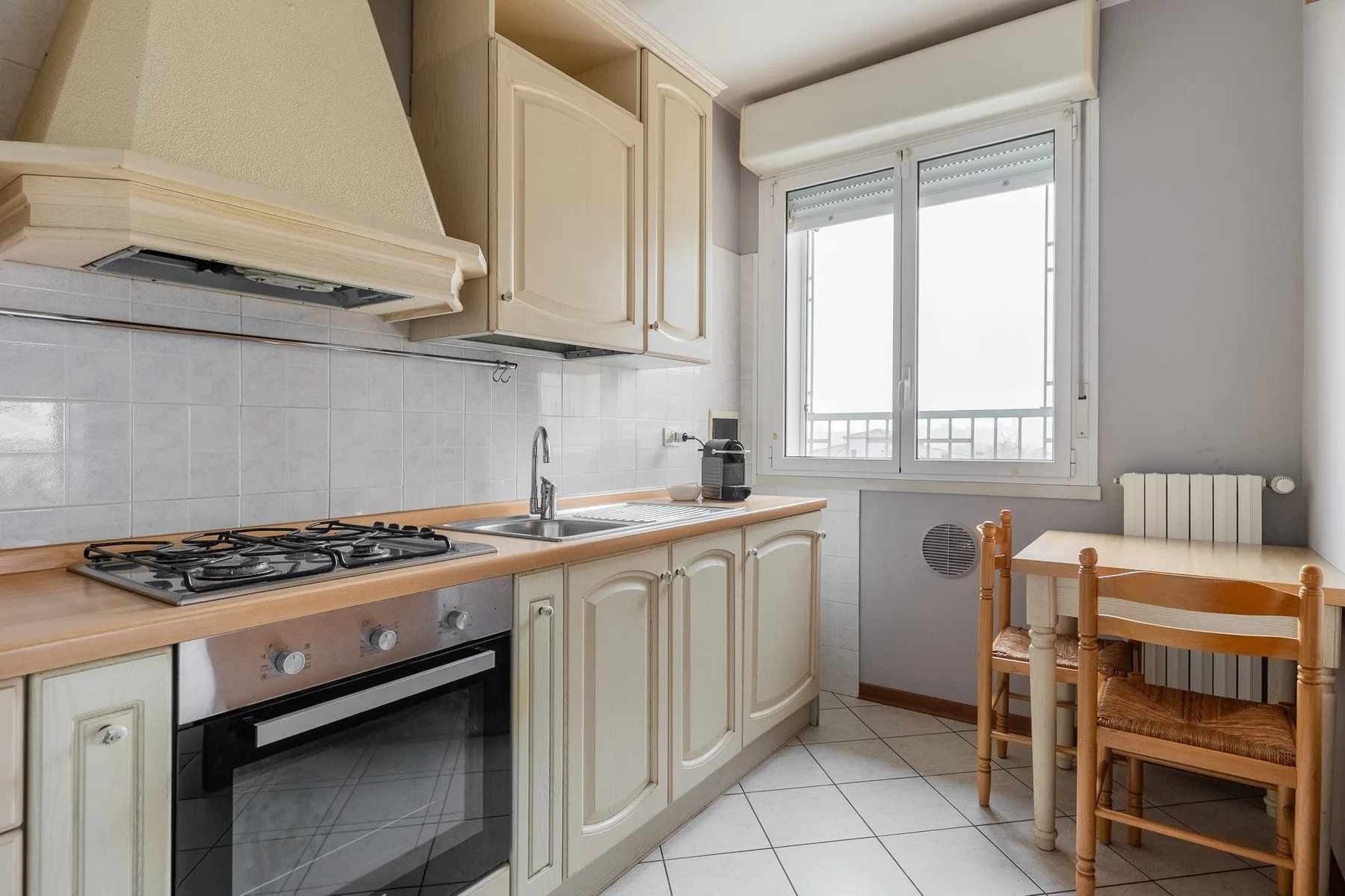A kitchen with a cooking range, sink, and a small dining table by the window.