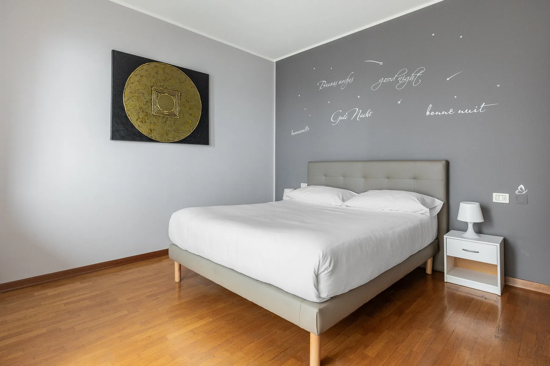 A bedroom with a neatly made bed and framed wall art.