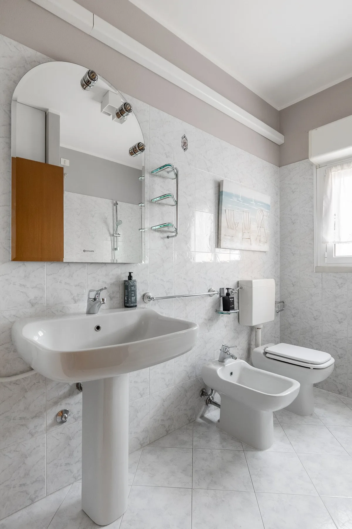 Un baño alicatado con lavabo de pedestal, inodoro y bidé.