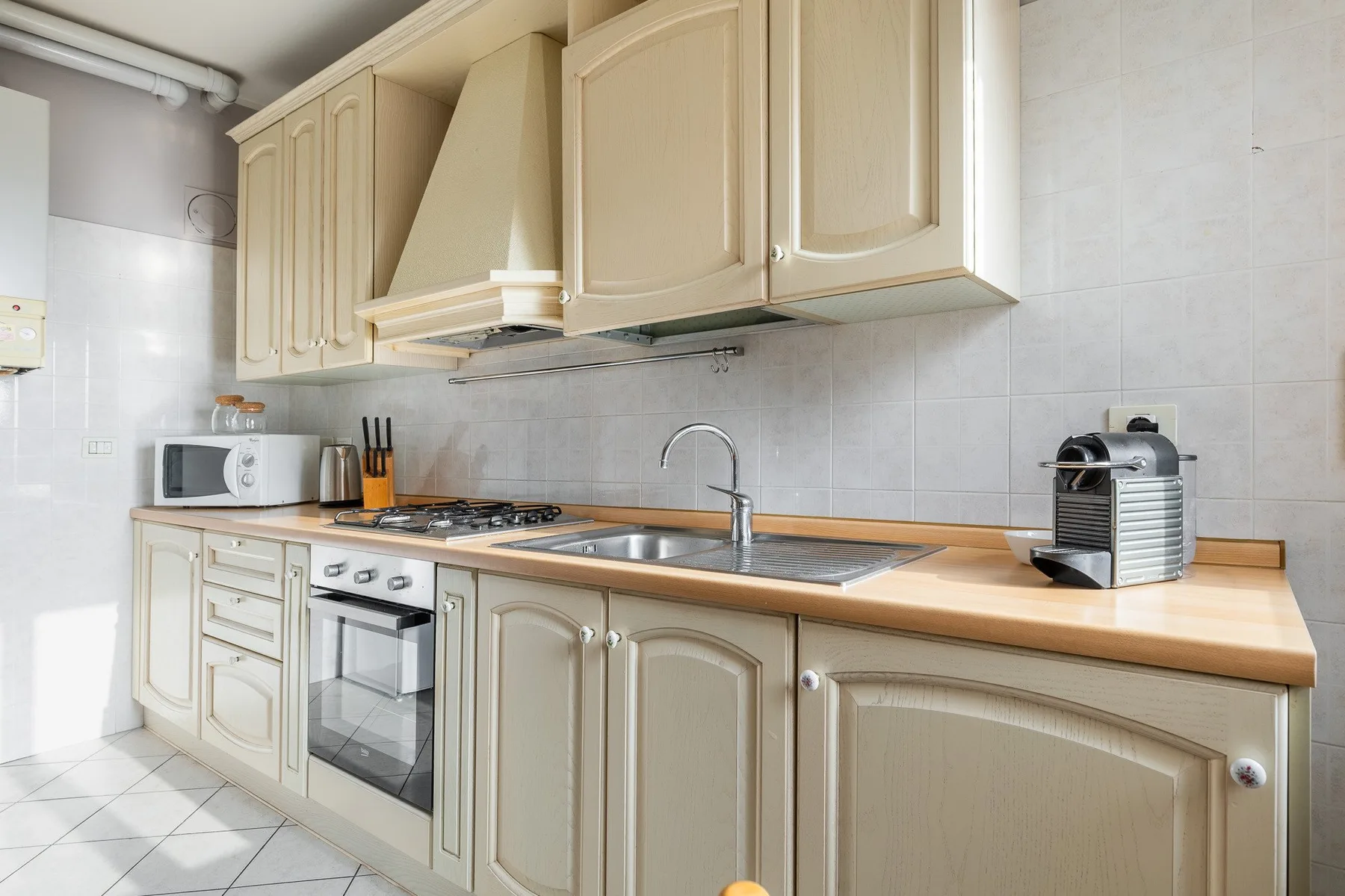 Una cocina luminosa con gabinetes color crema, una encimera y un horno integrado.
