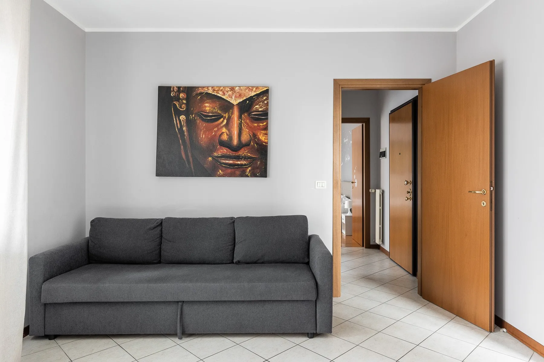 Una habitación de paredes grises con asientos oscuros bajo una obra enmarcada.