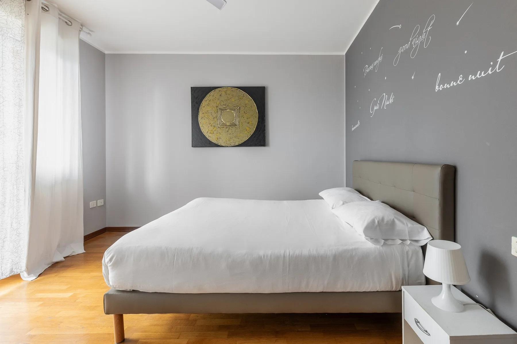 A bedroom with a neatly made bed and framed artwork on the wall.