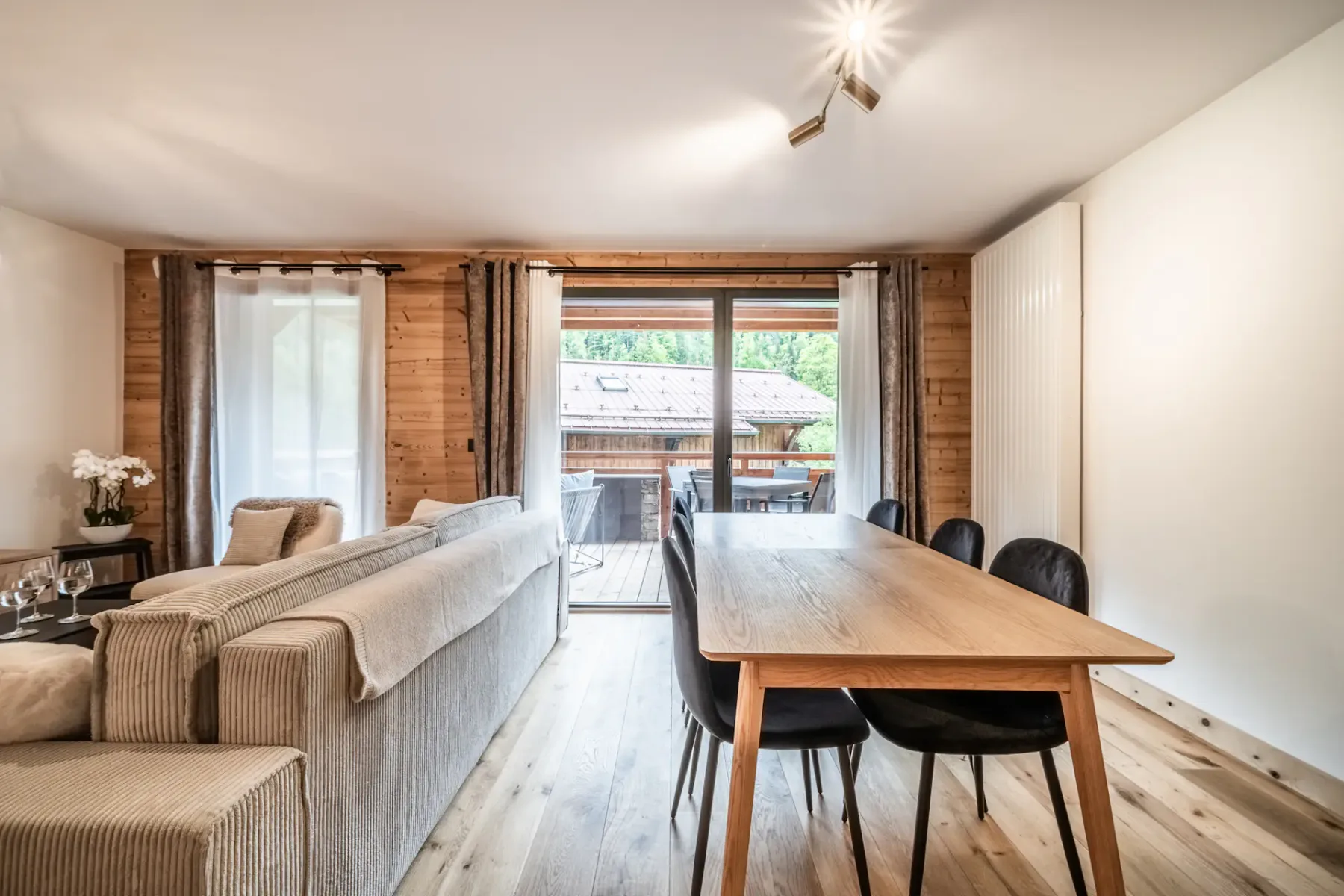 A living and dining area with a long table and sliding glass doors opening onto a patio.