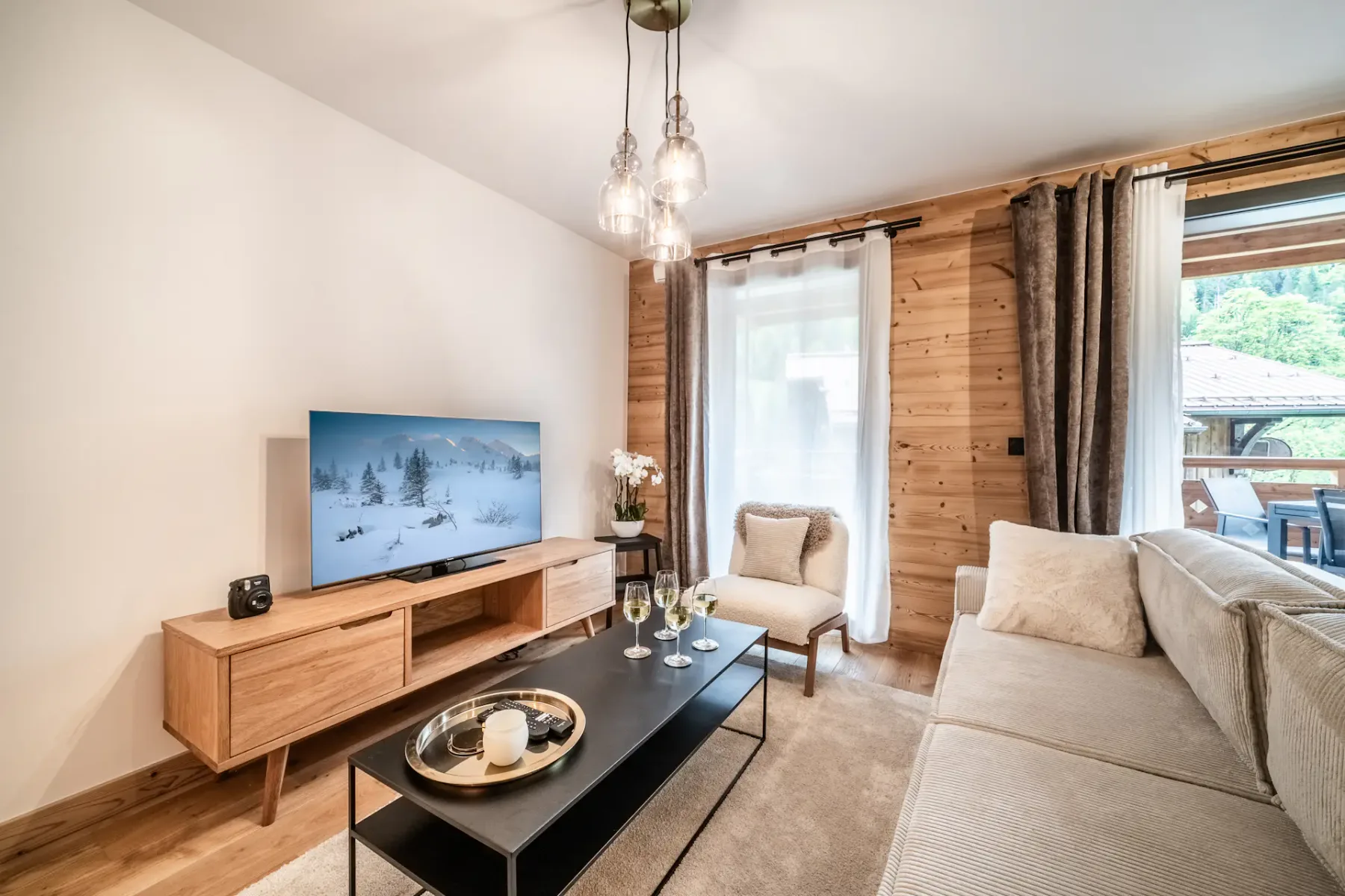 A living room with a television, coffee table, seating, and wooden wall panels.