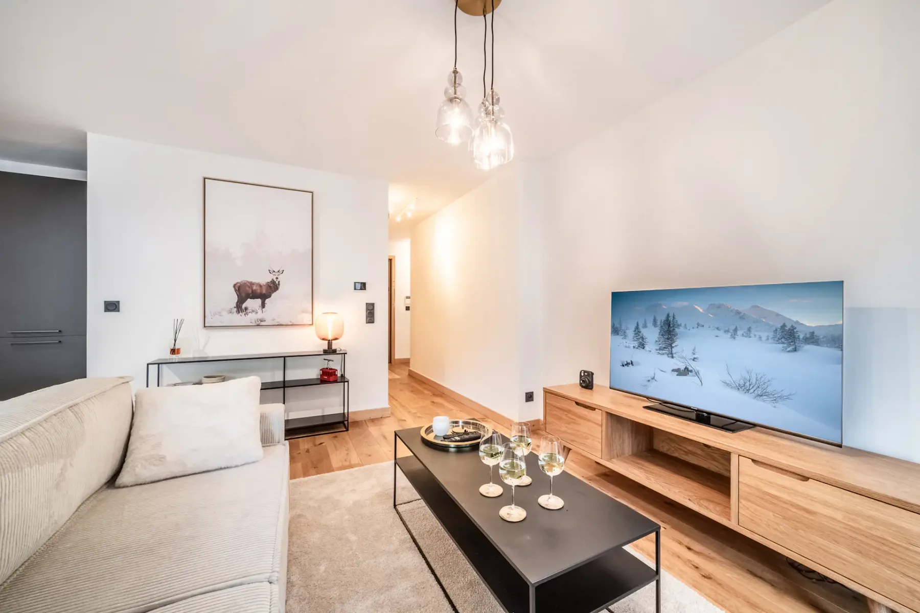 A bright living room with seating, a coffee table, and a television.