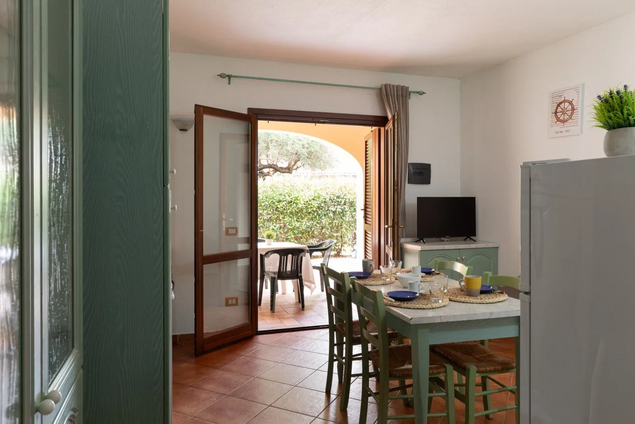 Comedor con una mesa y sillas junto a una puerta abierta que da a un patio.