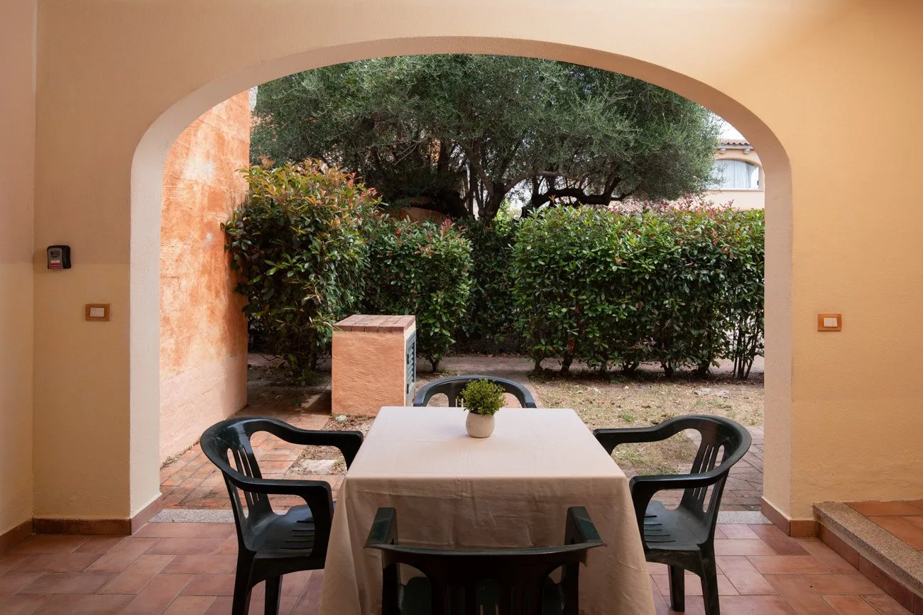 Un comedor en un patio cubierto, con mesa y sillas bajo un amplio arco.