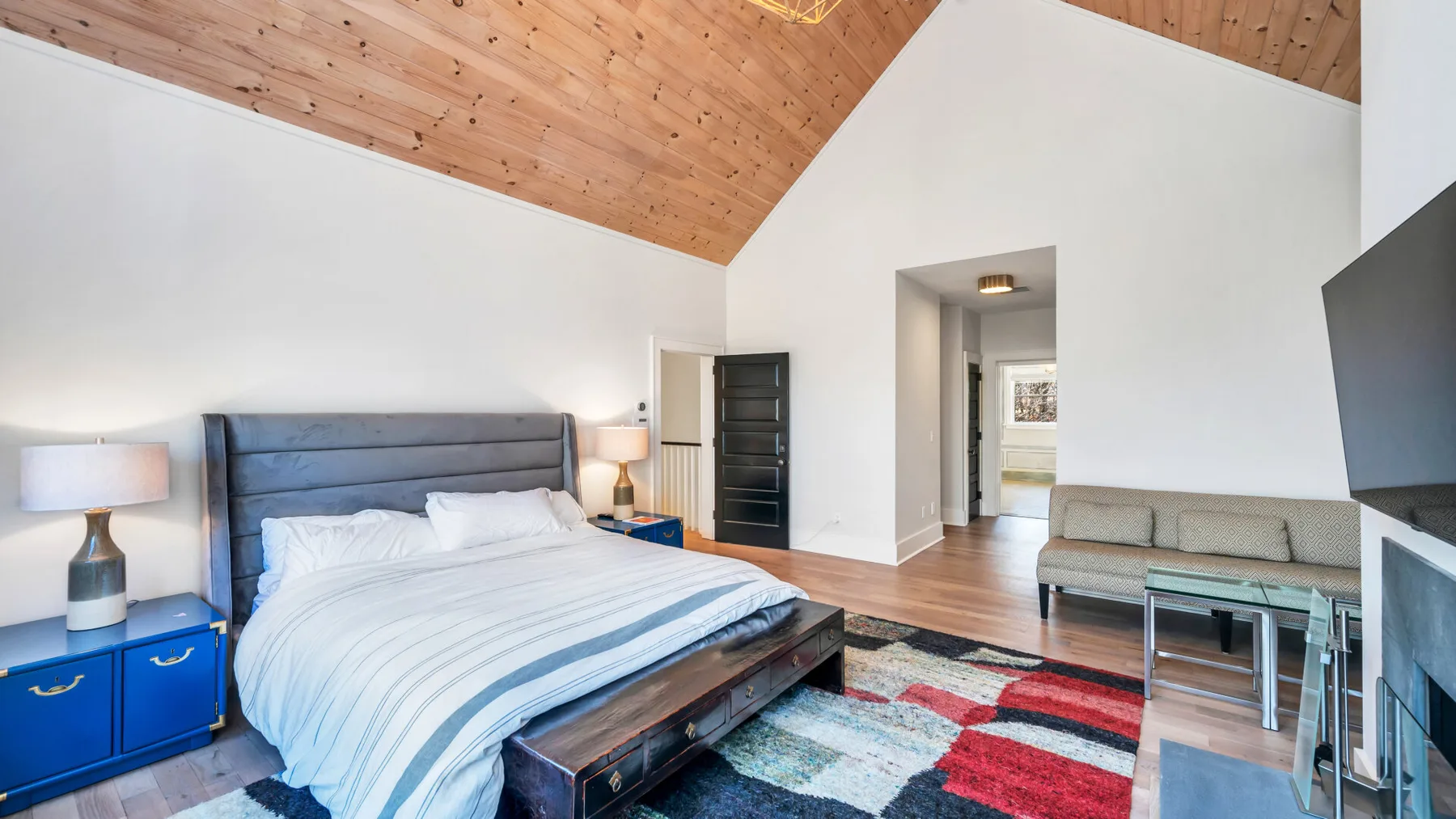Un dormitorio con una cama grande, mesitas azules y una alfombra colorida.