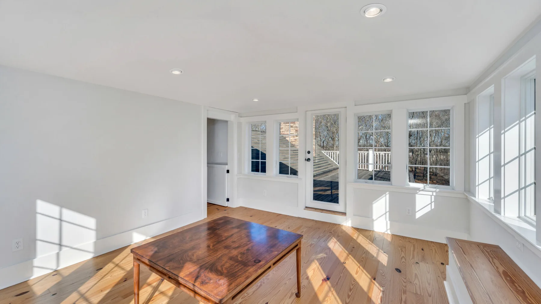Un salón luminoso con grandes ventanas y una mesa de centro de madera.