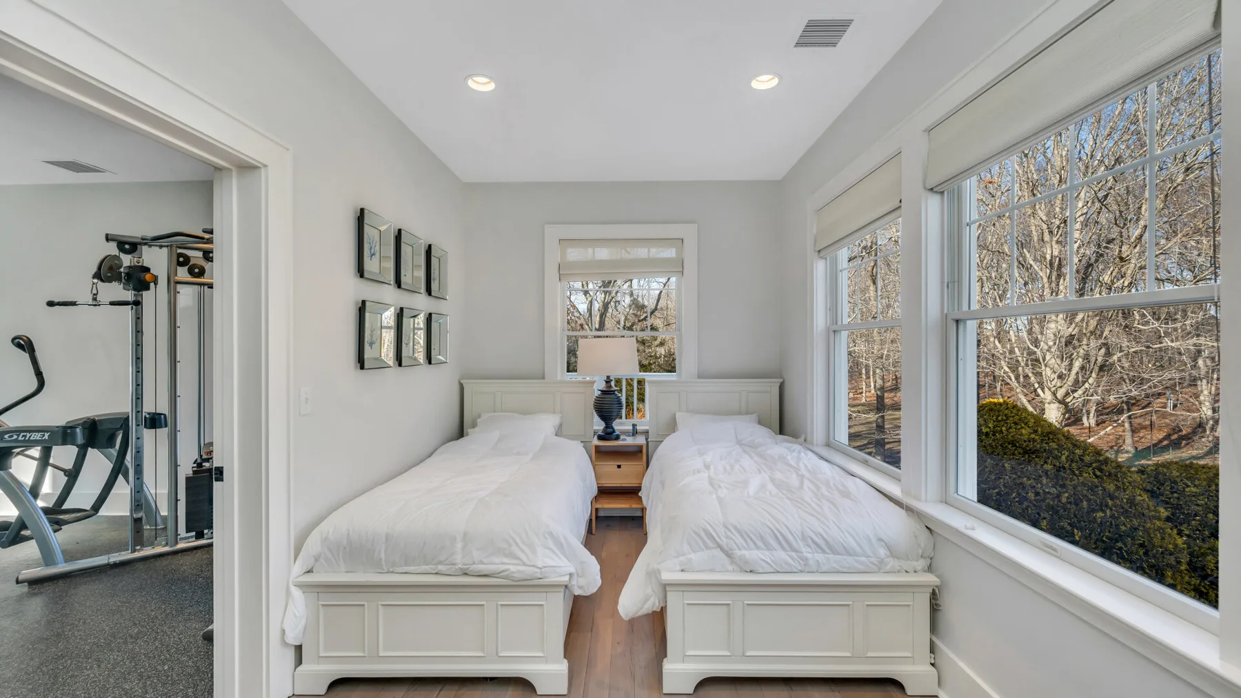 Un dormitorio luminoso con dos camas junto a grandes ventanas.