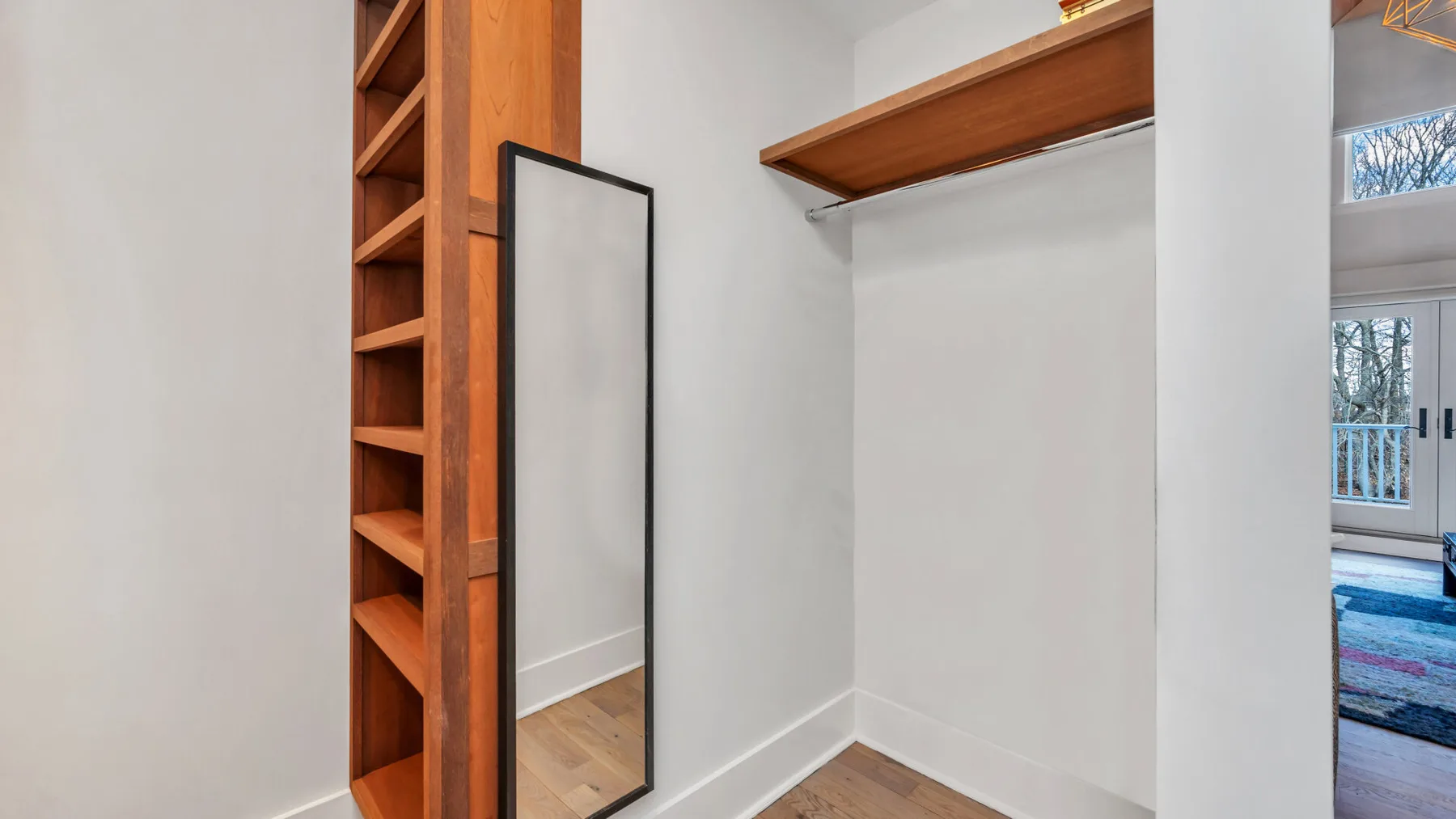 Un área de armario con estantes de madera abiertos y una barra para colgar.