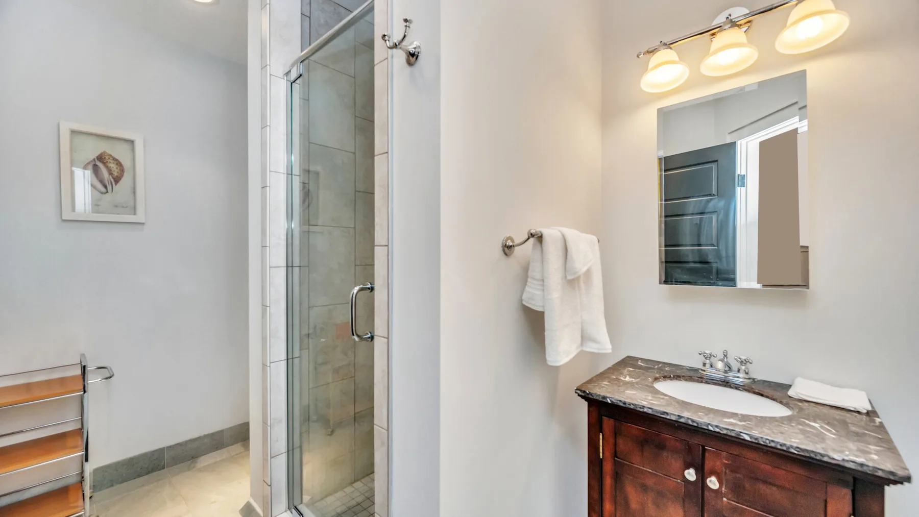 Un baño con ducha de vidrio, lavabo y espejo de pared.