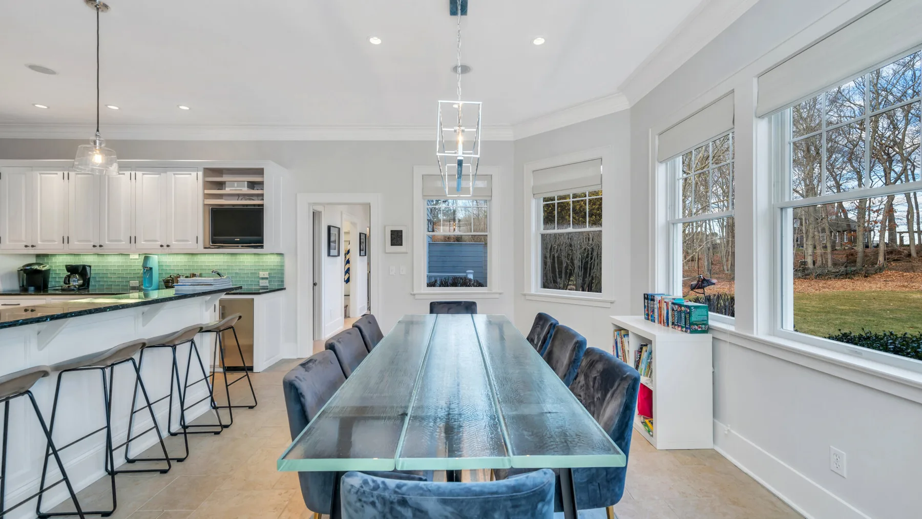 Un comedor luminoso con una mesa larga junto a una cocina abierta y grandes ventanas.