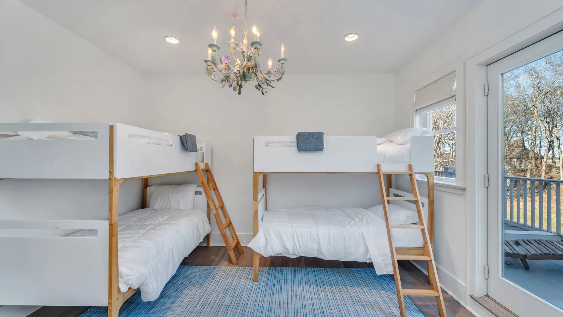 Un dormitorio luminoso con literas y una alfombra azul.