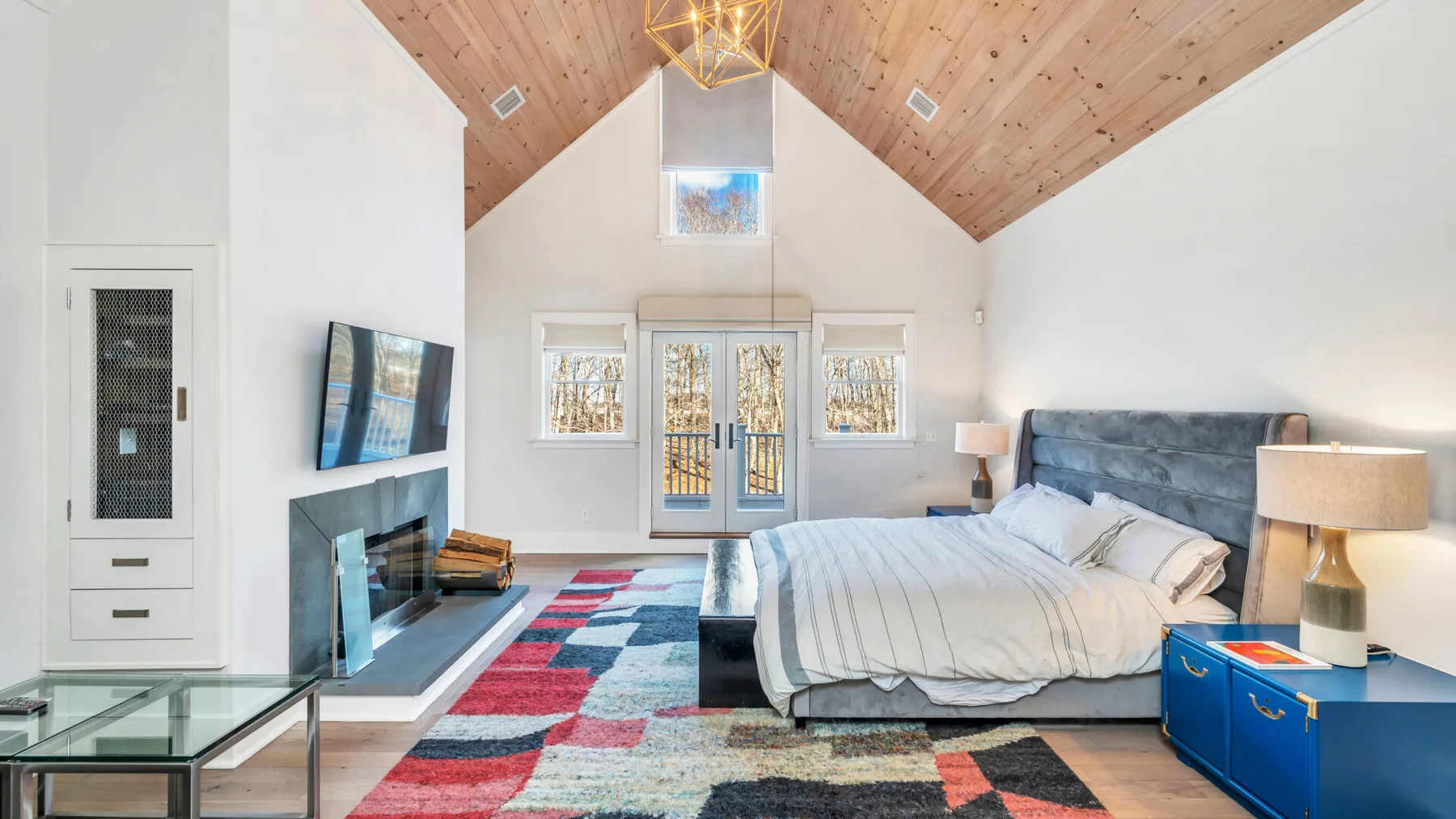 Un dormitorio luminoso con una cama, mesitas de noche y techo de madera inclinado.
