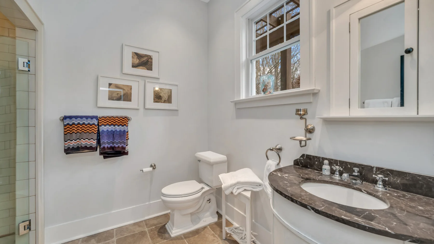 Un baño luminoso con lavabo, inodoro y cuadros en la pared.
