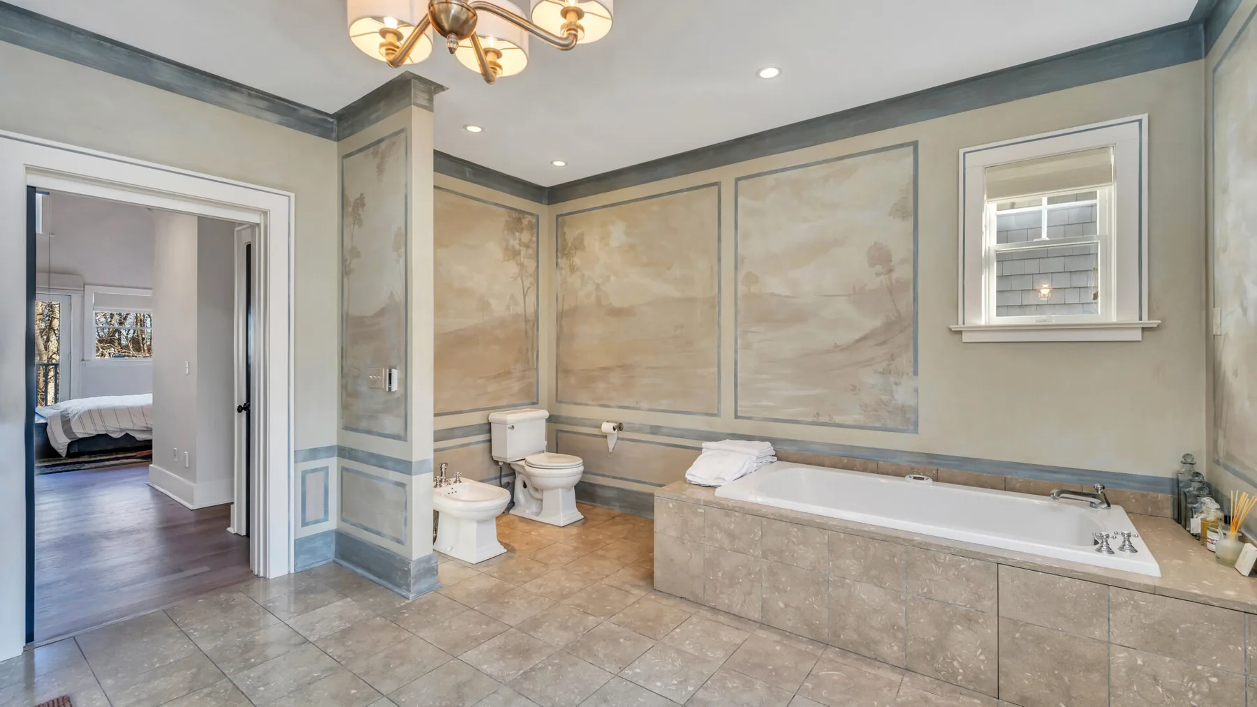 Un baño amplio cuenta con bañera, inodoro y paneles decorativos en las paredes.